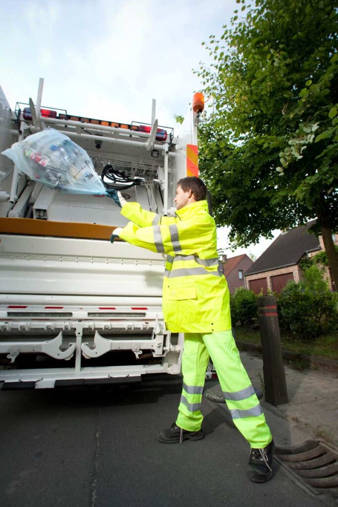 An operative throwing collected recycling into a collection vehicle